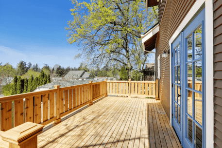 Modern wooden deck with railing overlooking suburban neighborhood on sunny day
