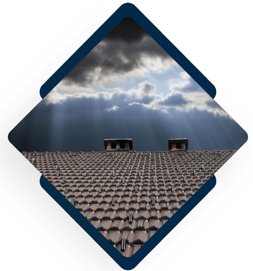 Tile roof with chimneys under dramatic stormy sky with sunbeams breaking through clouds