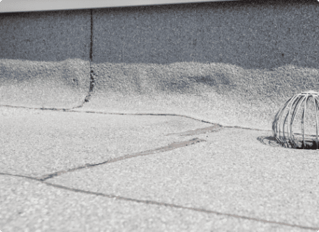 Cracked concrete sidewalk with metal drain grate showing urban infrastructure wear