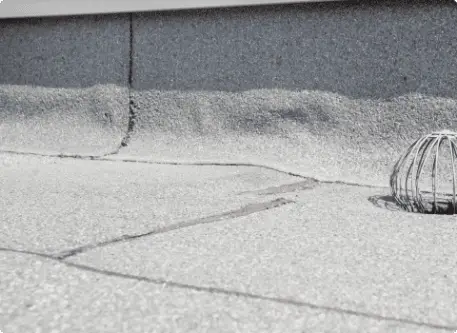 Cracked concrete sidewalk with metal drain grate showing urban infrastructure wear