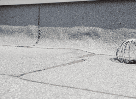 Cracked concrete sidewalk with metal drain grate showing urban infrastructure wear