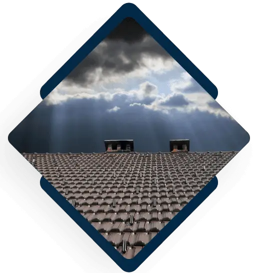 Tile roof with chimneys under dramatic stormy sky with sunbeams breaking through clouds
