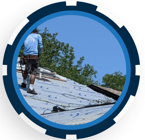 Roofer installing shingles on residential roof with blue sky and trees background