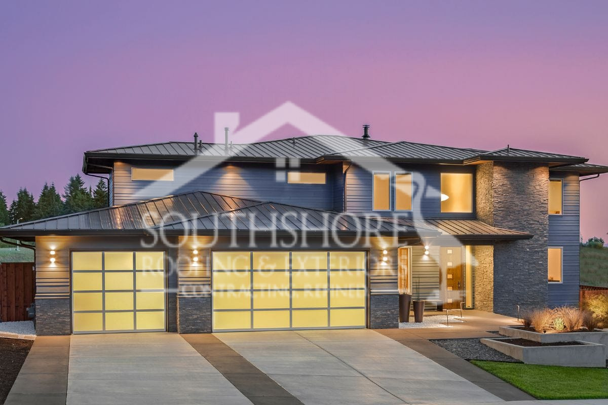Modern luxury home with glass garage doors and stone accents at twilight