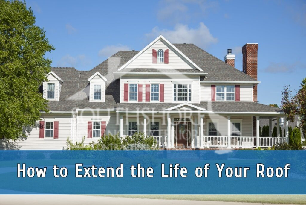 White colonial house with red shutters and wraparound porch under blue sky