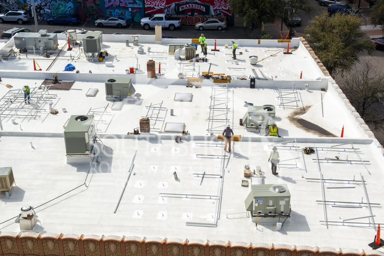 Aerial view of commercial rooftop construction with workers and HVAC equipment