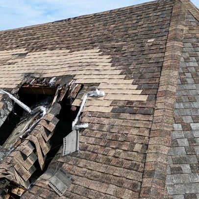 Roof with significant damage and exposed beams from shingle loss.