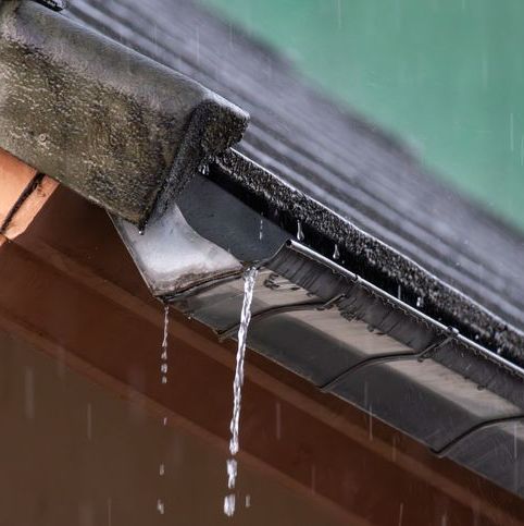 Rainwater flowing from house roof gutter during rainfall.
